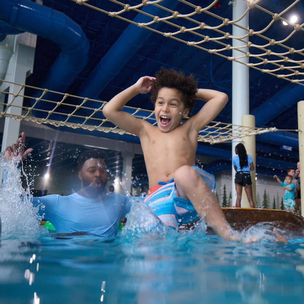boy jumps in the pool as parents watch excitedly