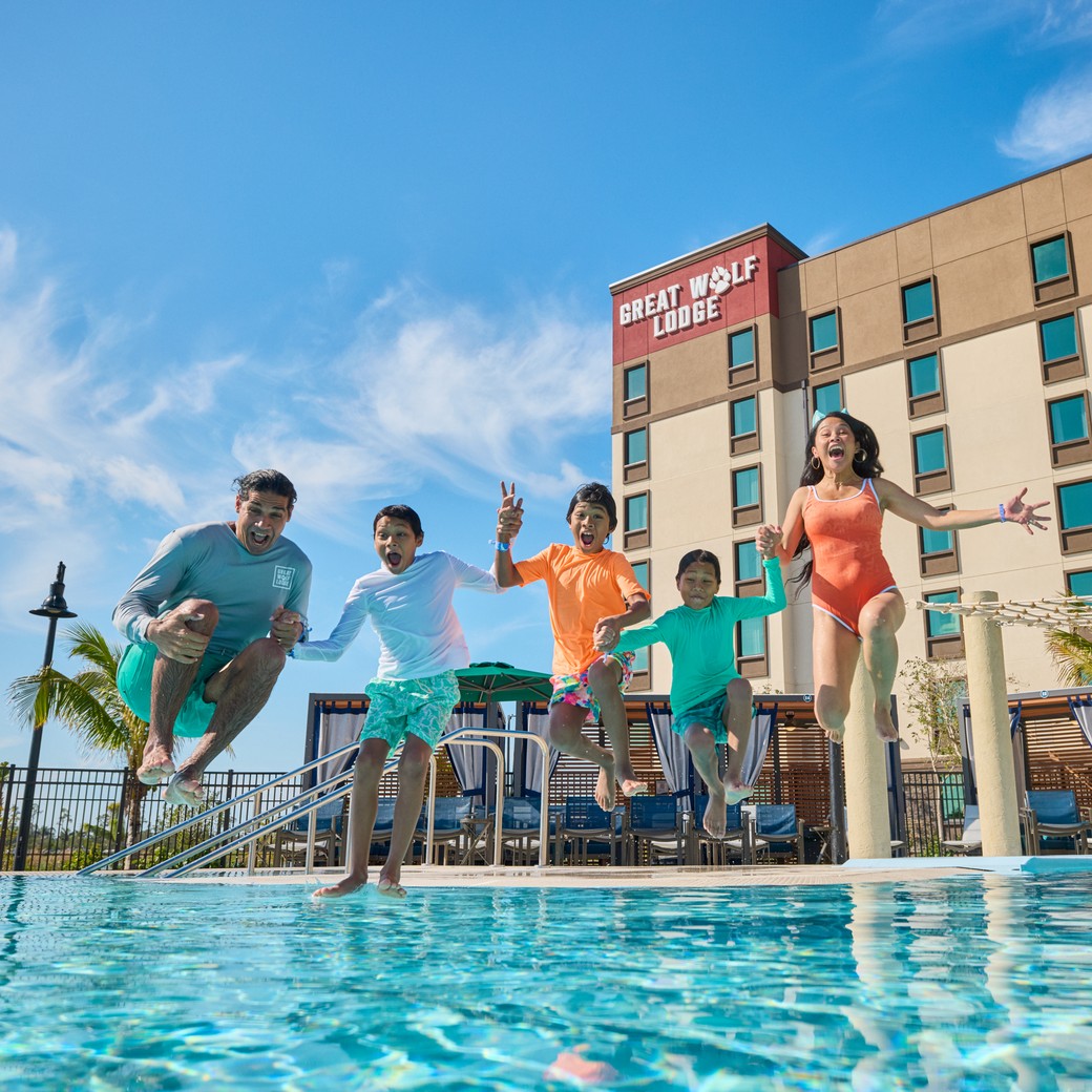 A happy family jumping into an outdoor pool