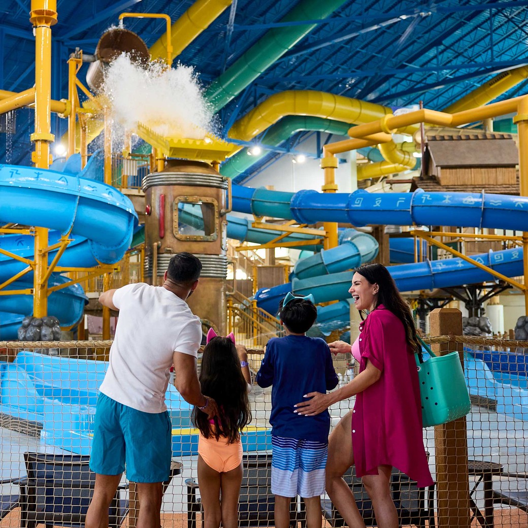 family enjoying water falling from a big bucket at a indoor water park