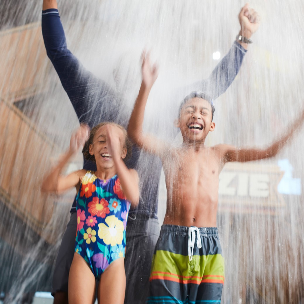 family standing as water splashes from top
