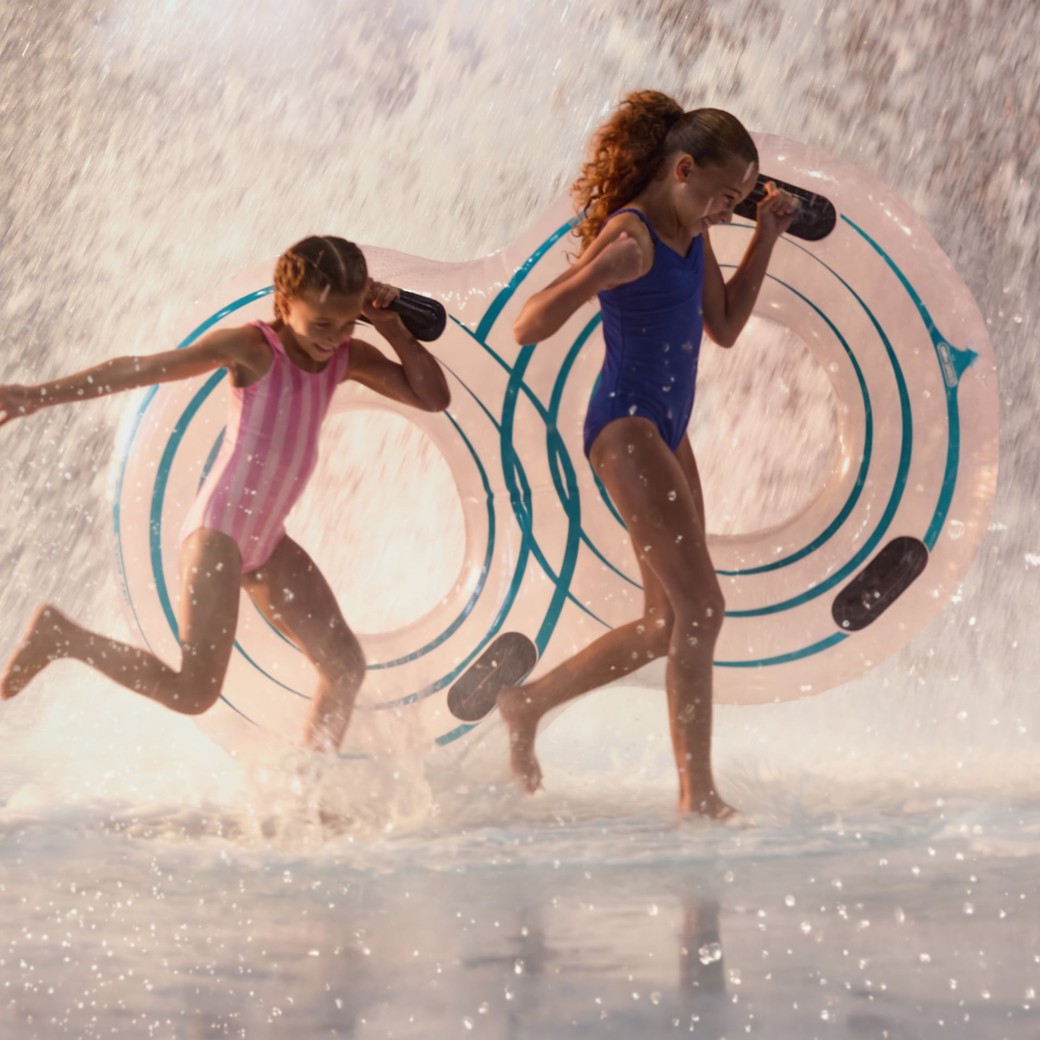 Children playing in water with splash feature and toys.