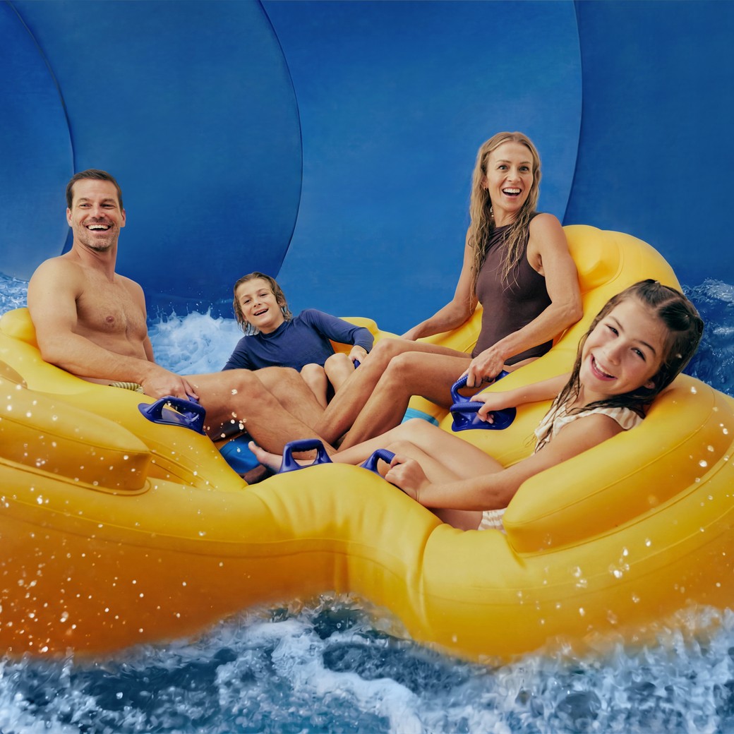Family enjoying water park slide on yellow floats.