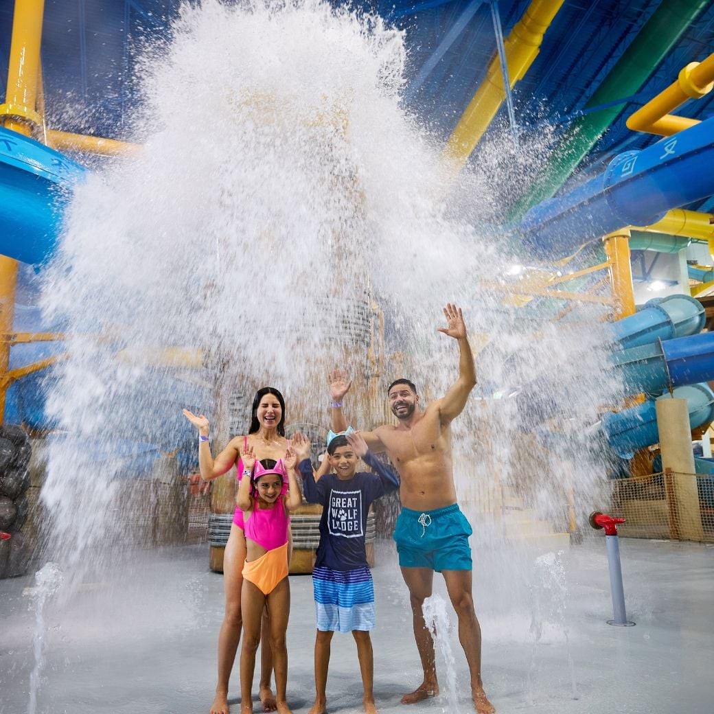 family standing under water bucket and getting soaked with water
