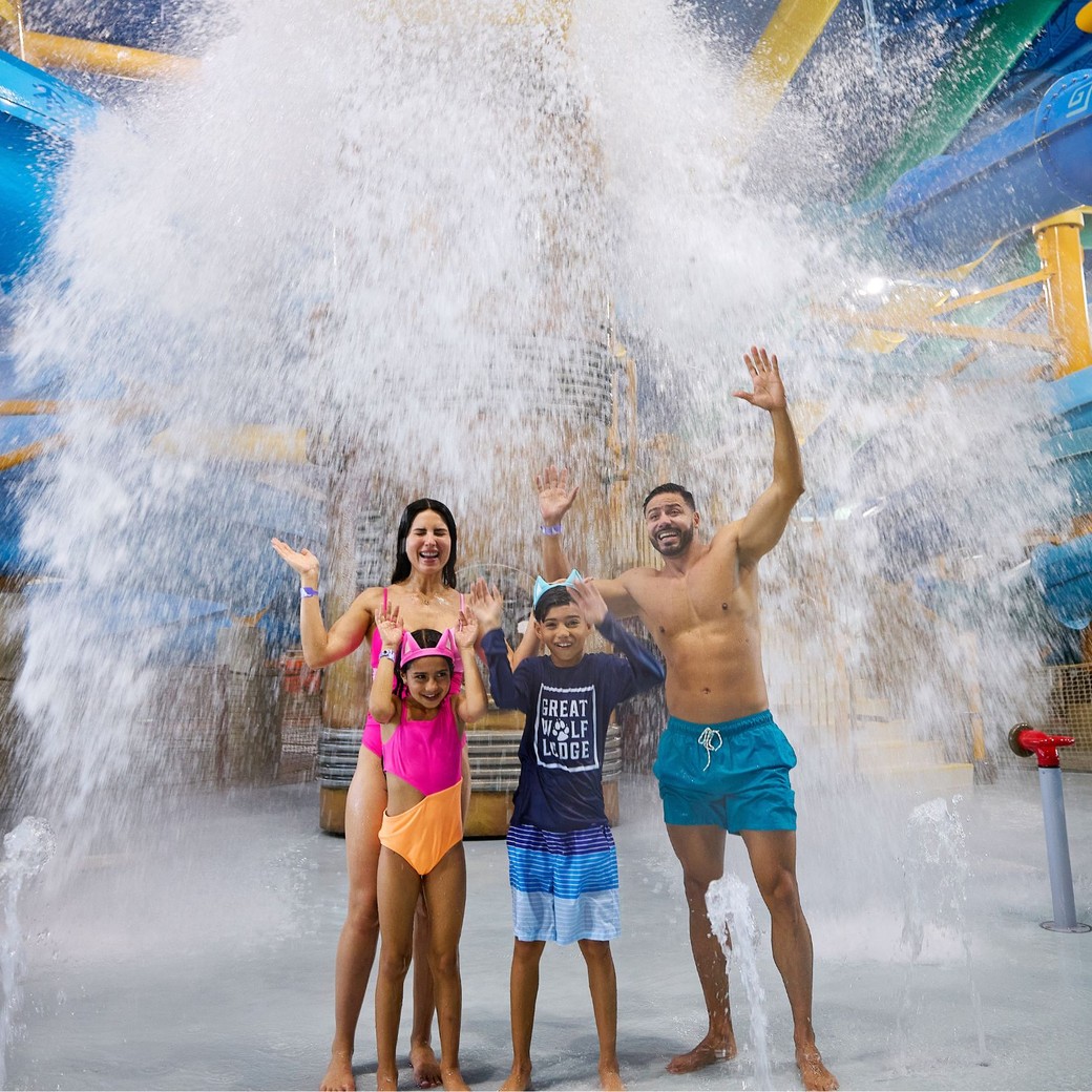 family enjoying as water falls from a big bucket
