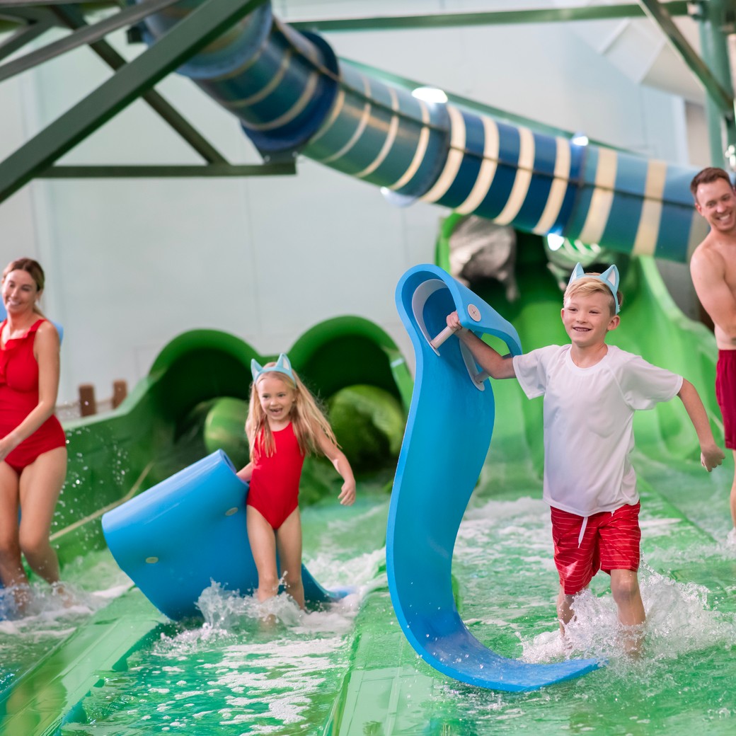 family sliding down a water slide using mats