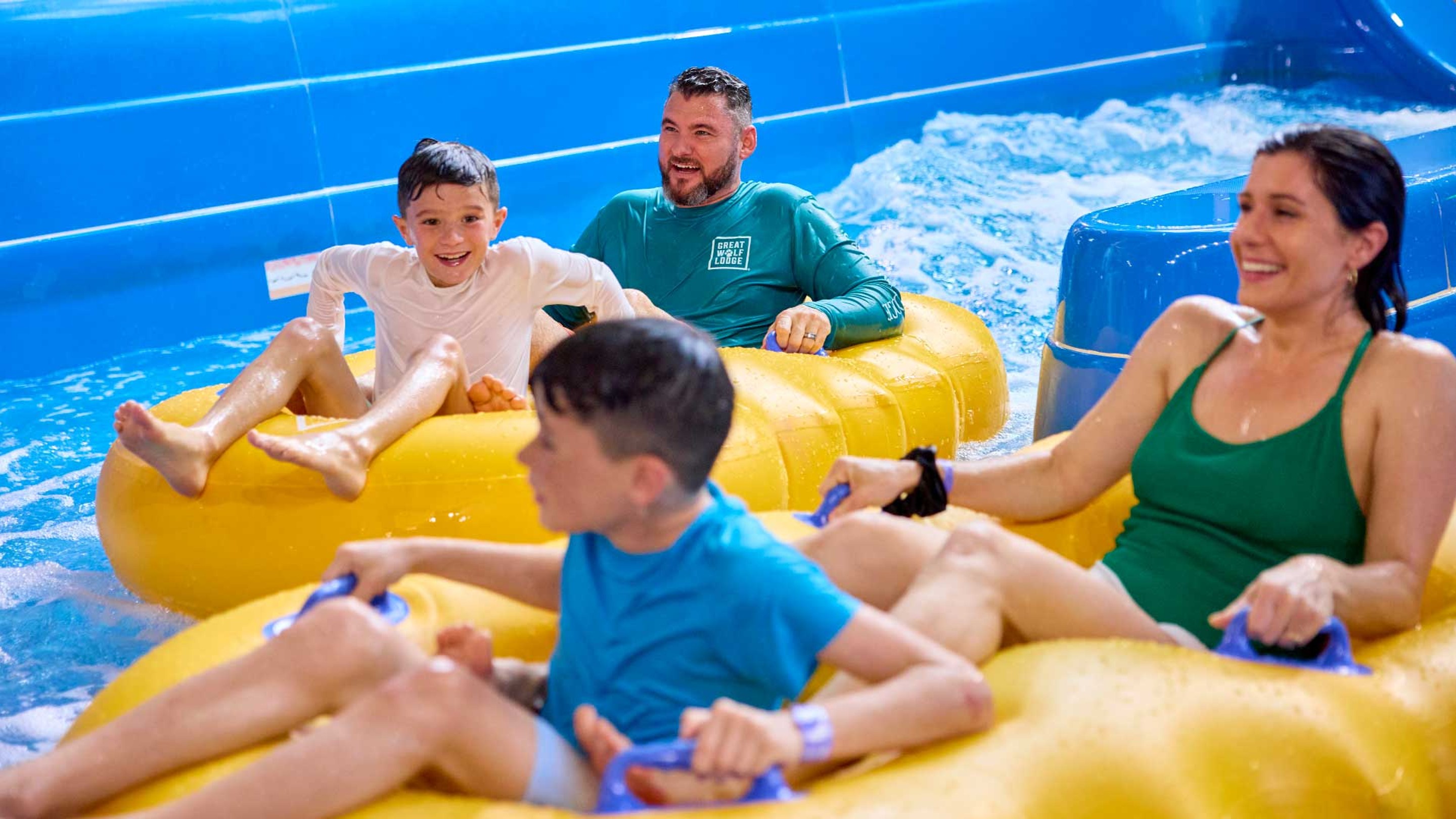 family enjoying as they slide down a water slide riding on mats