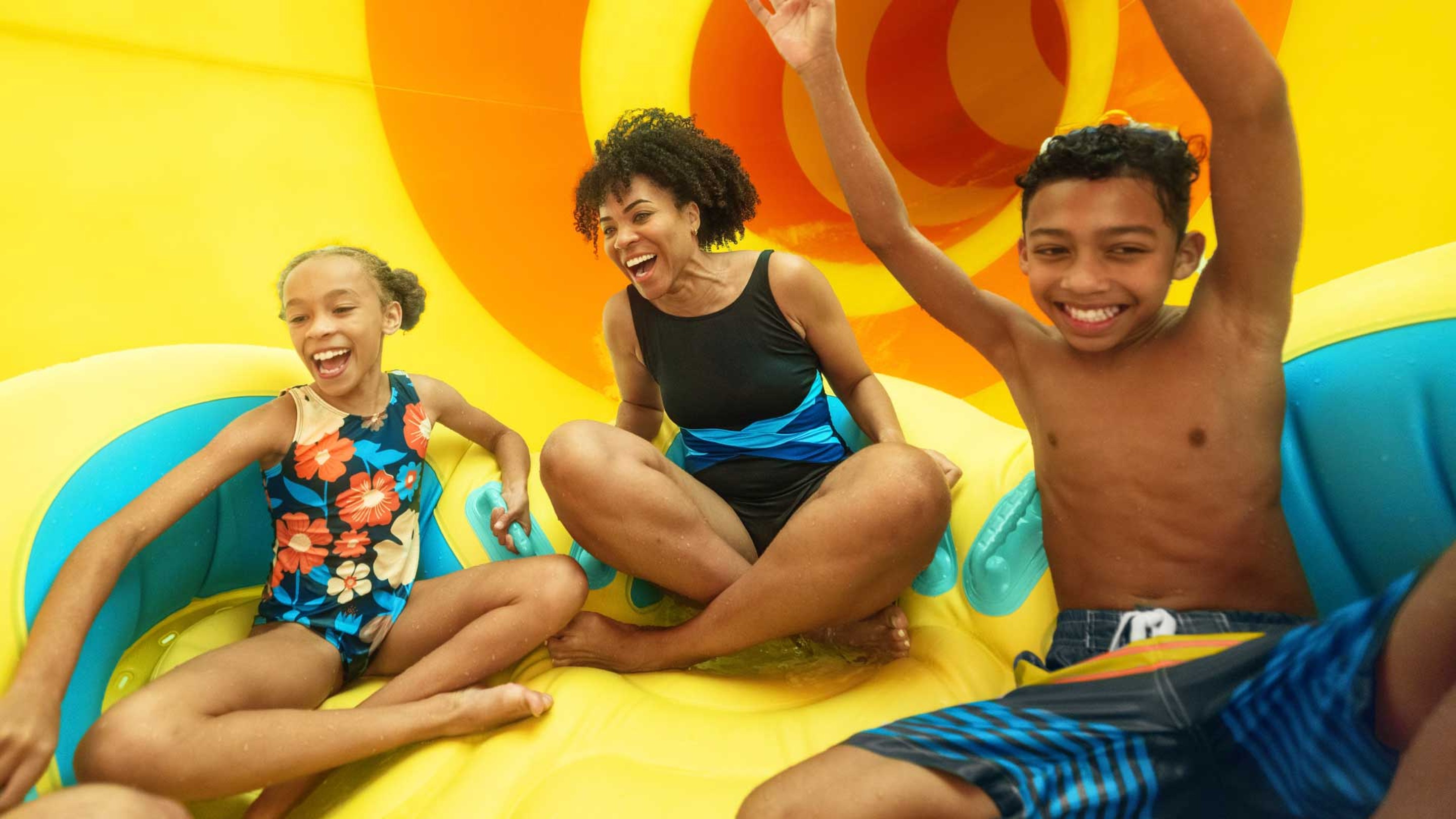 mother and children enjoying a water slide riding a tube
