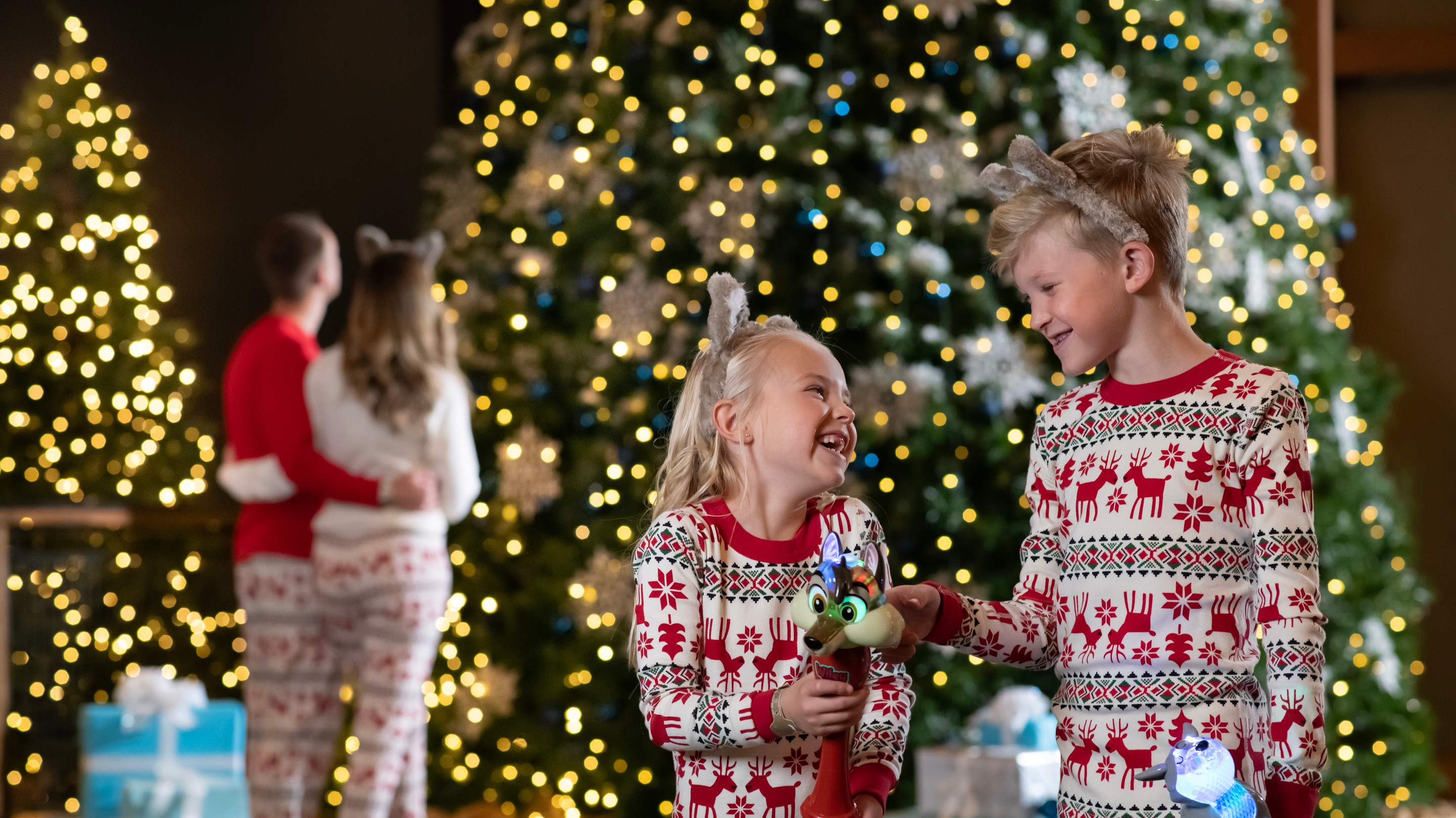 family standing in front of Christmas trees feeling joyed