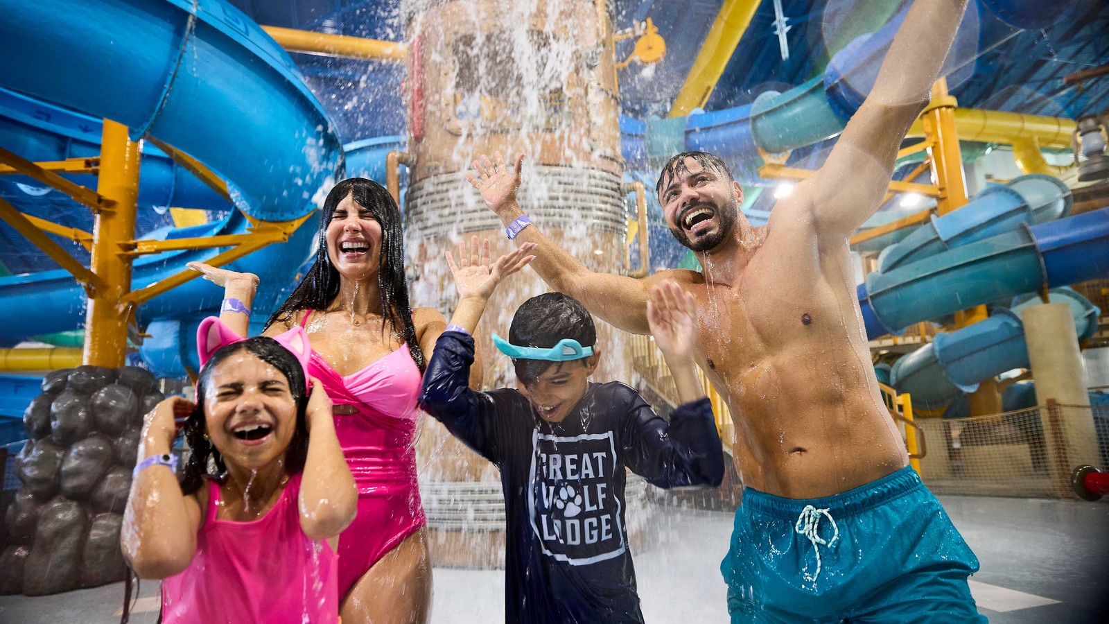 family feeling happy as they get soaked in water from the tipping bucket above them in a waterpark