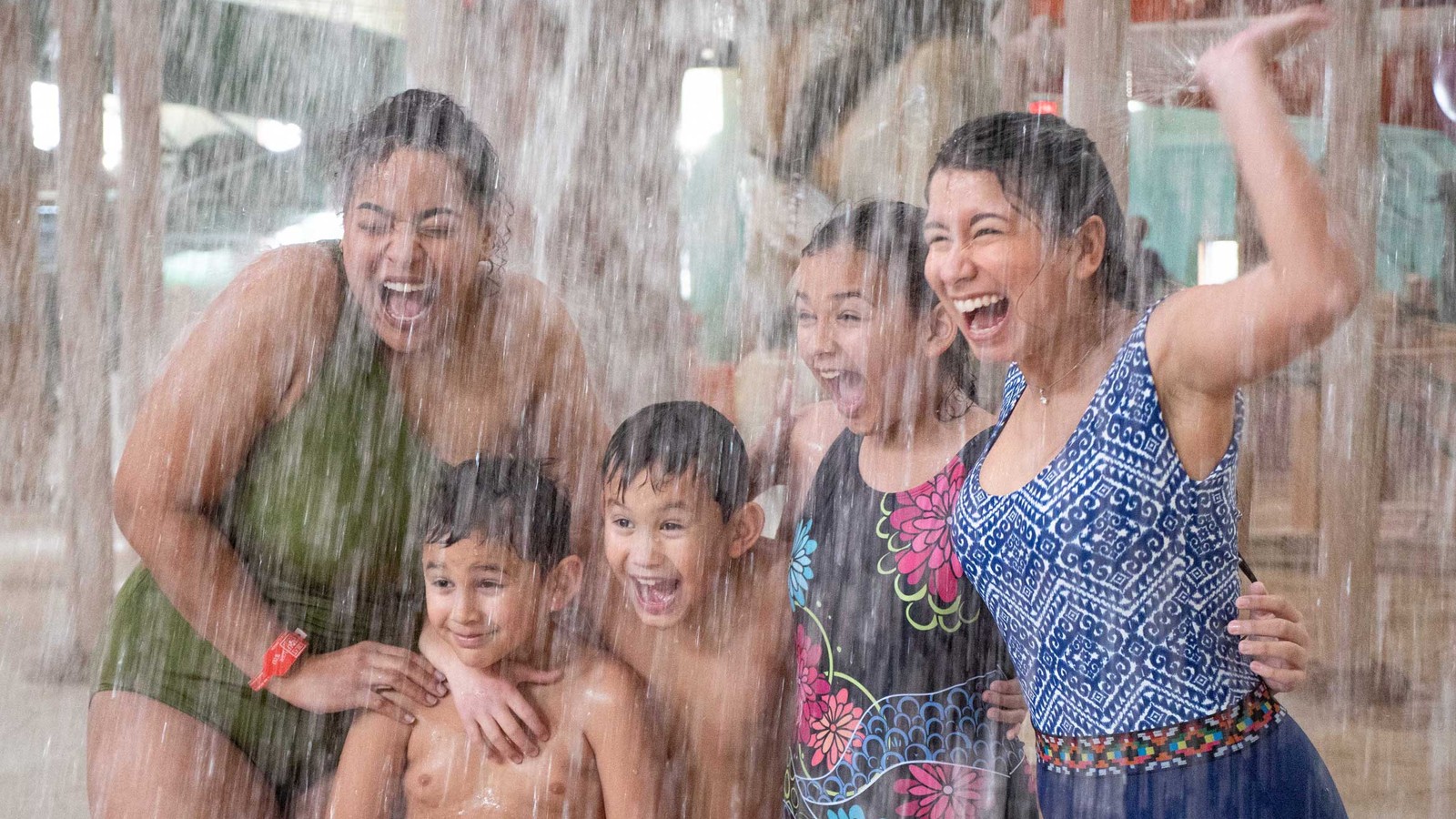 family standing under water bucket splashing water 