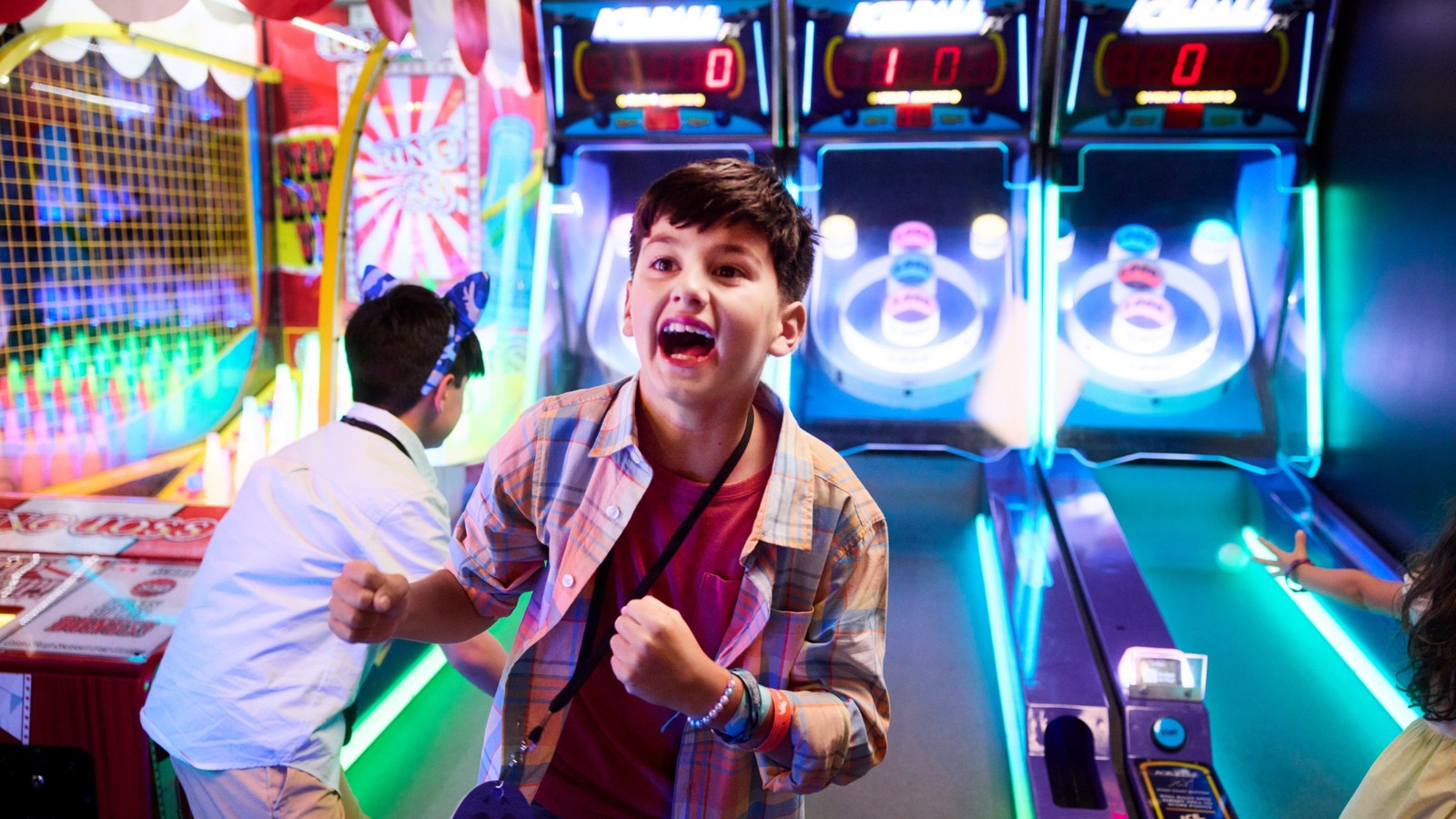 Boy celebrating while playing arcade basketball game