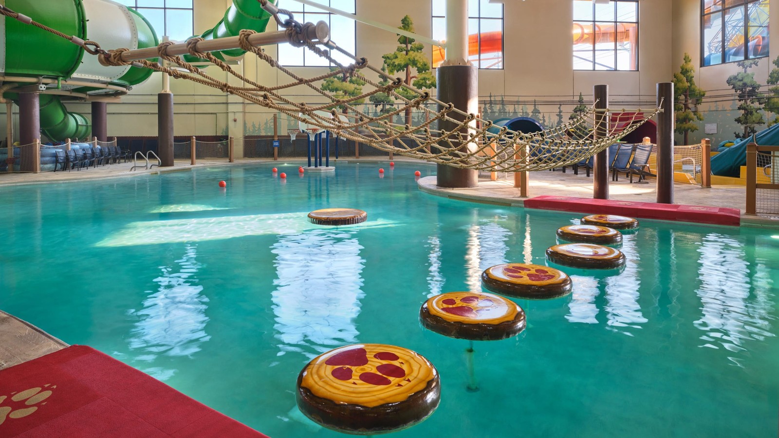 A girl balances on a lily pad float in indoor pool
