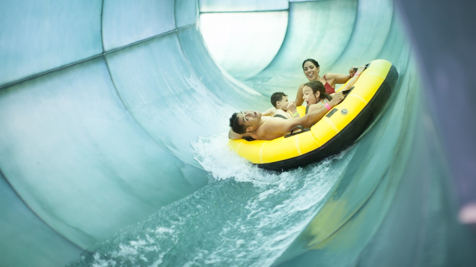 Family of four rides down waterslide in yellow tube
