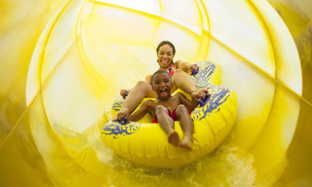 Mother and son in a tube racing down a yellow waterslide 