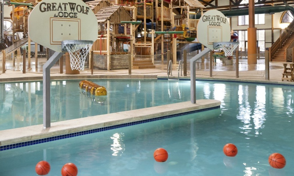 A large indoor water park featuring multiple slides and a basketball hoop for recreational activities.