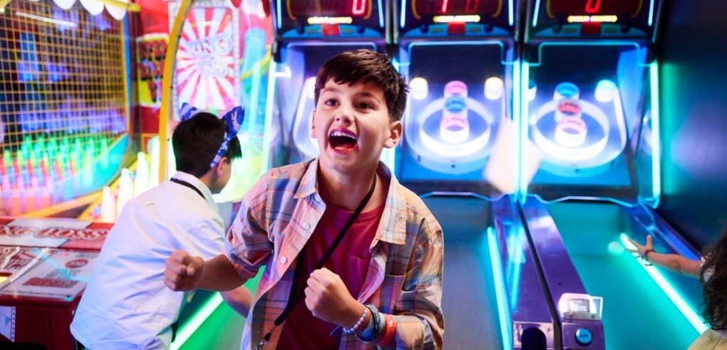 Boy celebrating while playing arcade basketball game