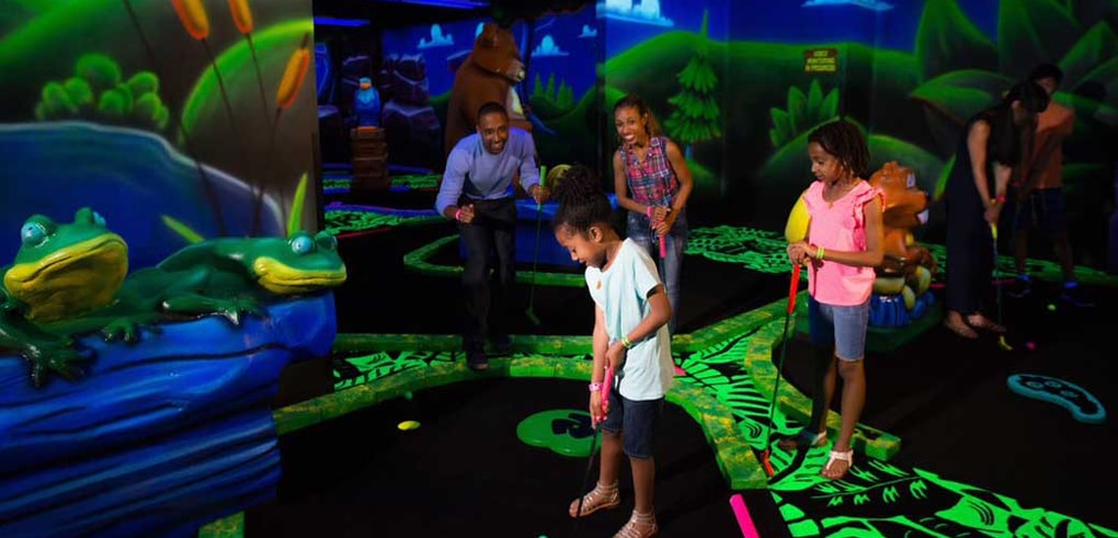 A family plays glow in the dark mini golf at Great Wolf Lodge