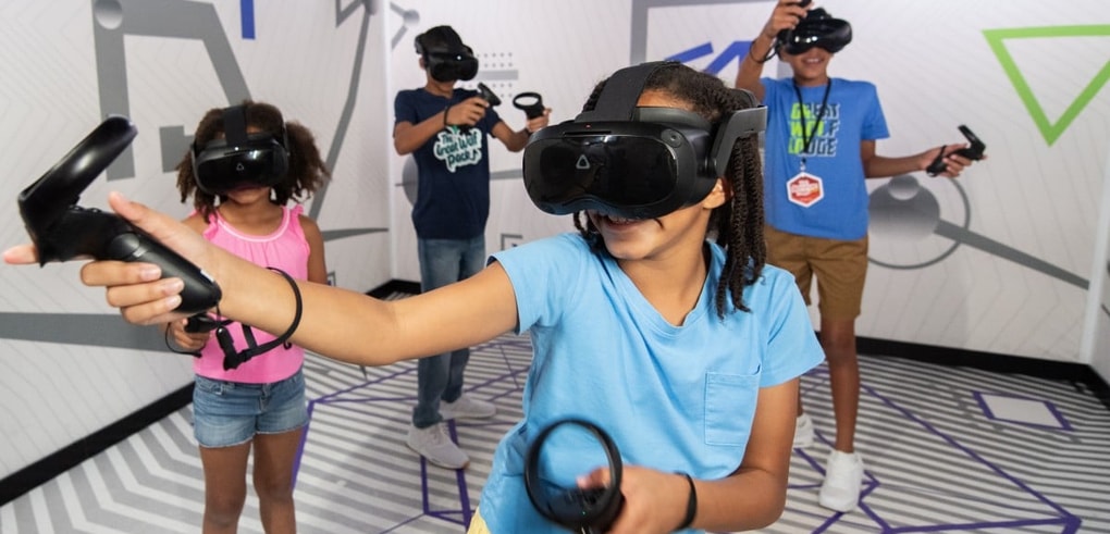 Kids wearing VR headsets play with controllers indoors