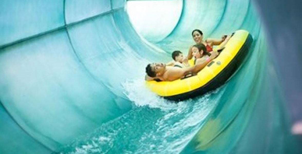 Family of four rides down waterslide in yellow tube