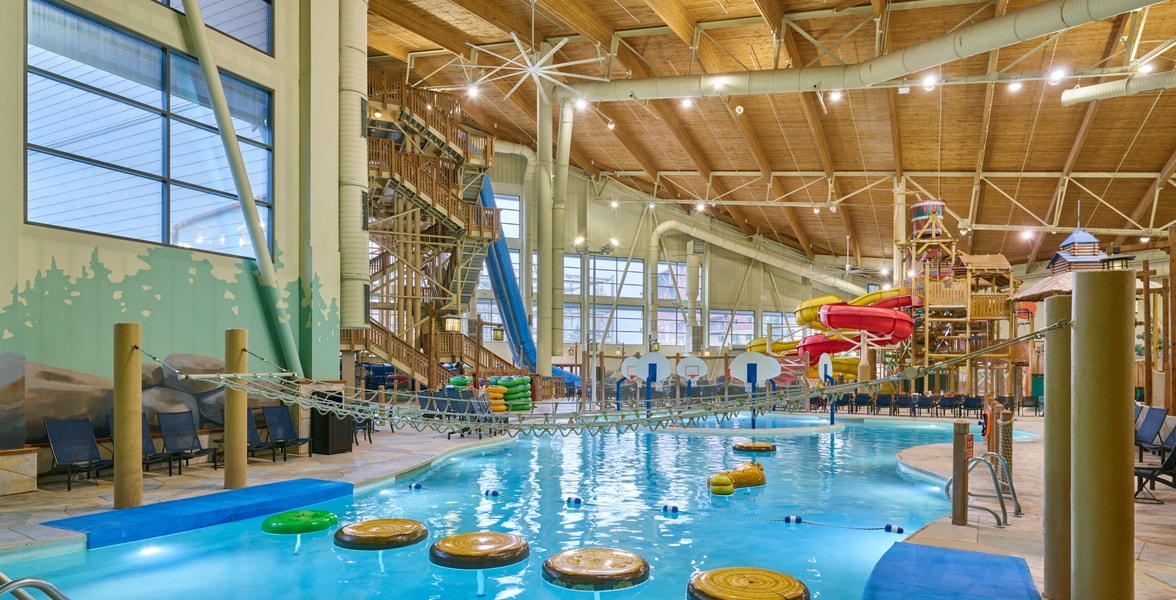 A girl balances on a lily pad float in indoor pool