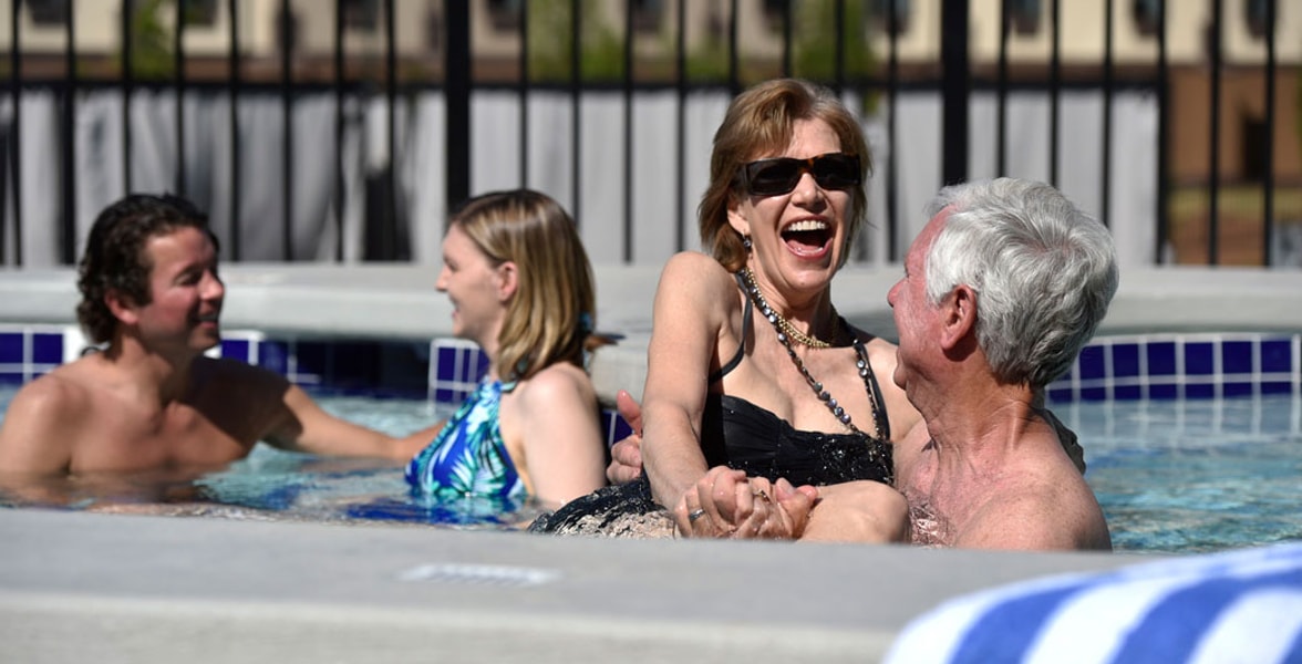 A couple relax in and on the side of the indoor pool 
