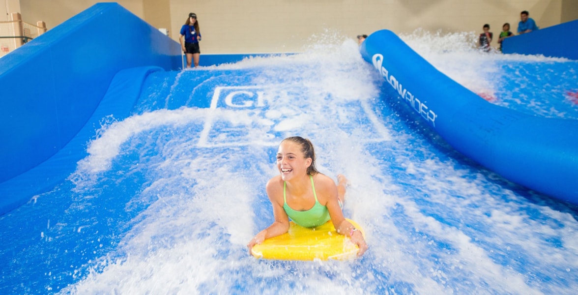 A child rides on a yellow boogie board in the water attraction 