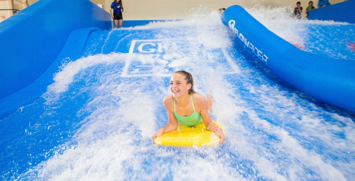 A child rides on a yellow boogie board in the water attraction