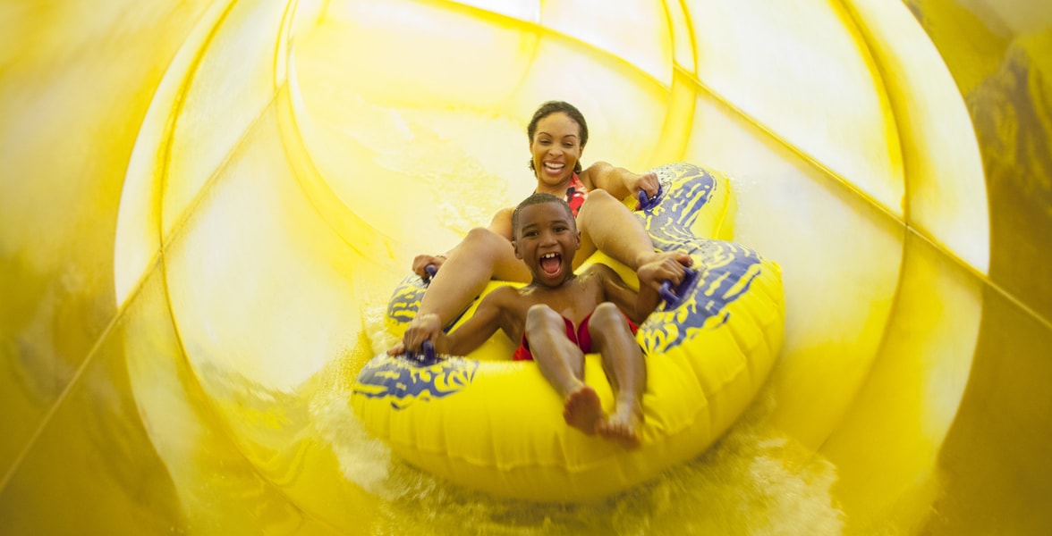 Mother and son in a tube racing down a yellow waterslide