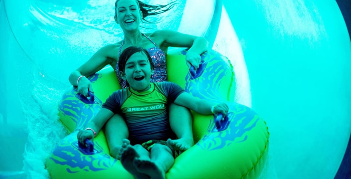Mother and son in a tube racing down a yellow waterslide 