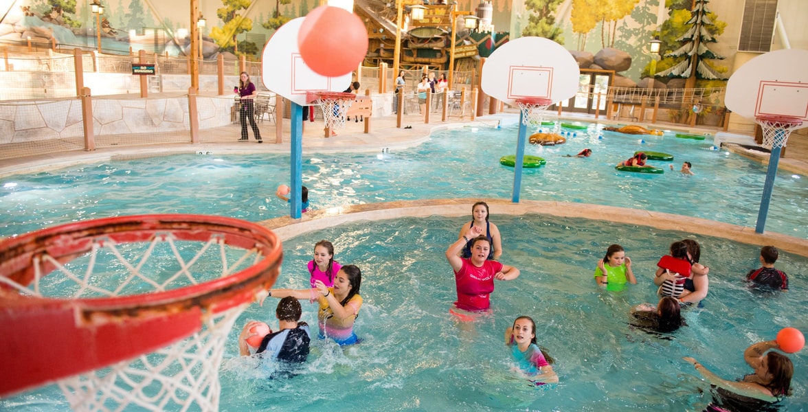 family playing basketball in indoor pool 