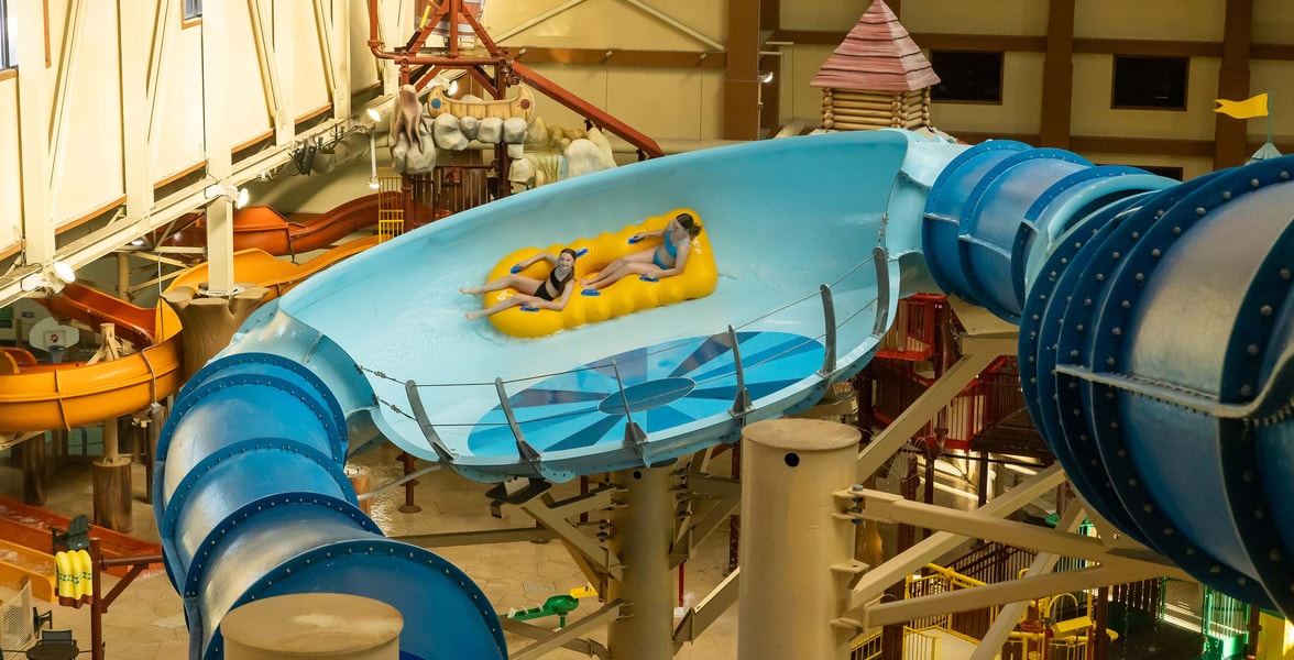 Two teenagers riding a yellow raft in an indoor water park