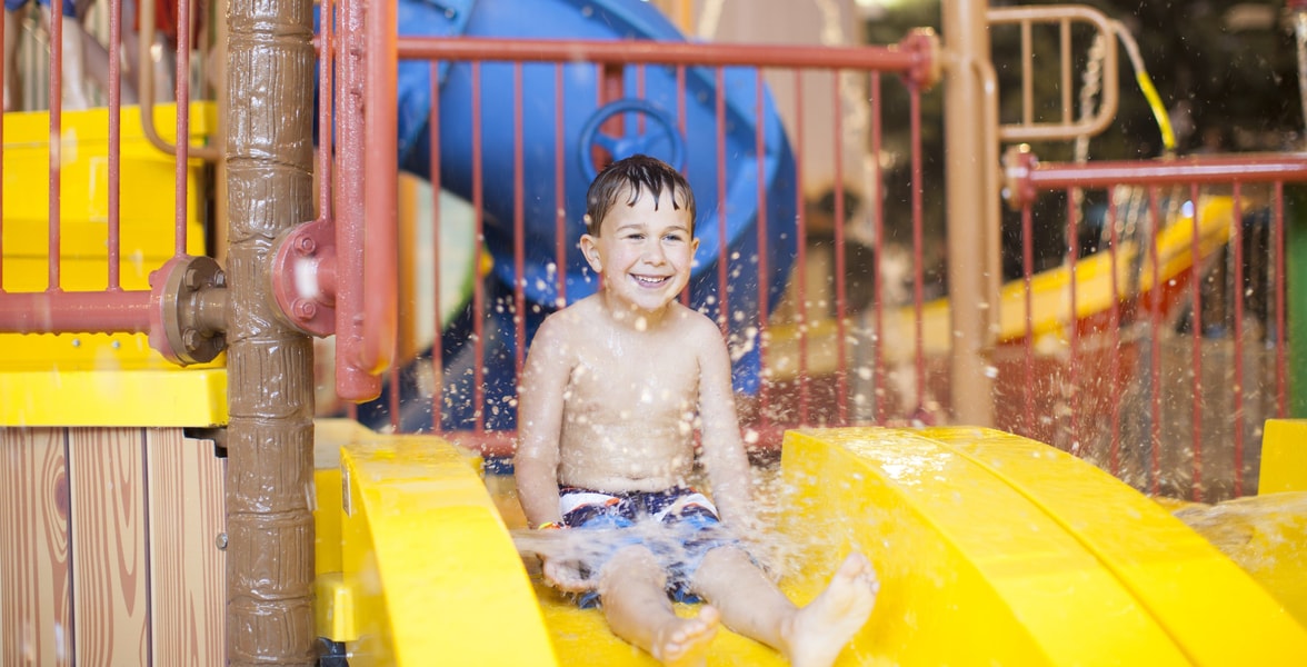 little boy about to go down a yellow kiddie slide