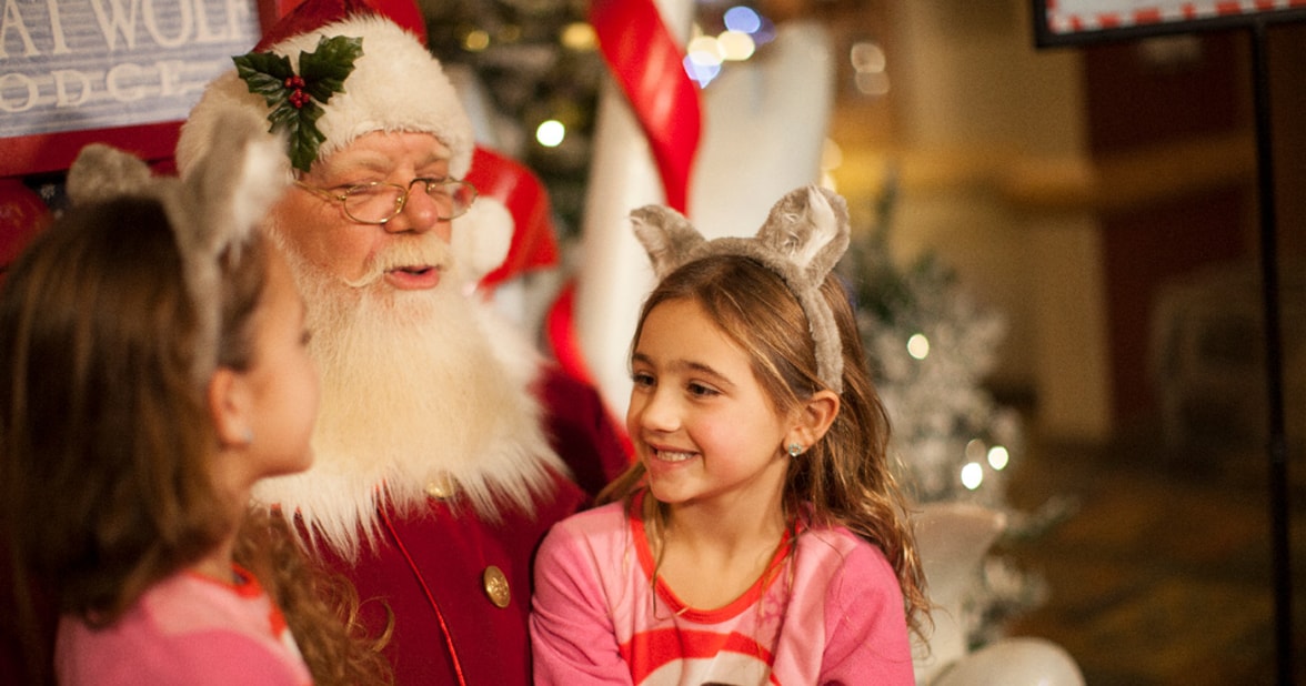 two kids smiling and sitting on Santa's laps