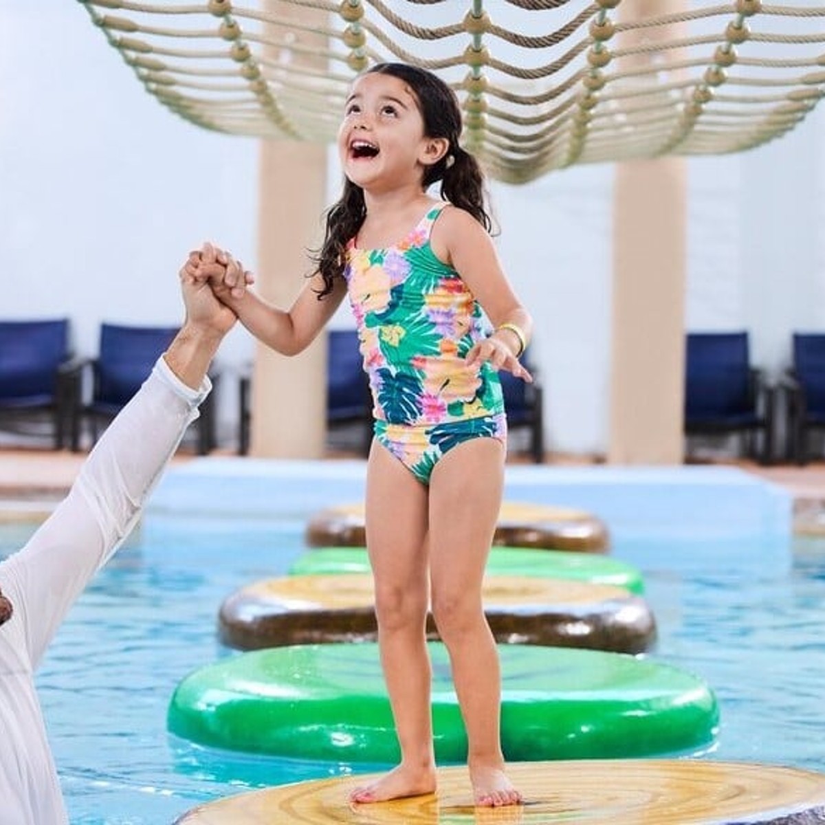 little girl holding her dad's hand while walking on lily pads
