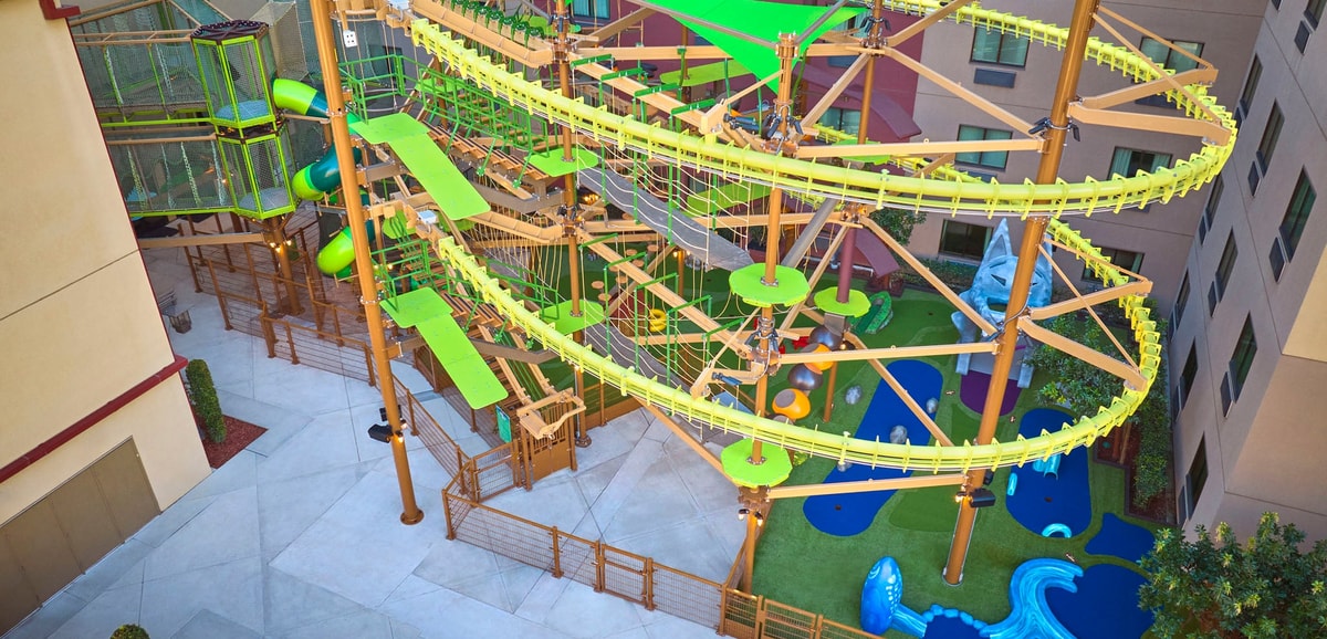 Young girl with a pink shirt navigating indoor ropes course