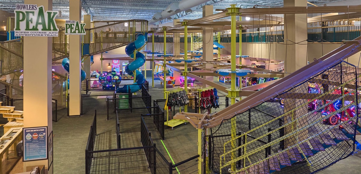Three women navigating indoor ropes course with harnesses