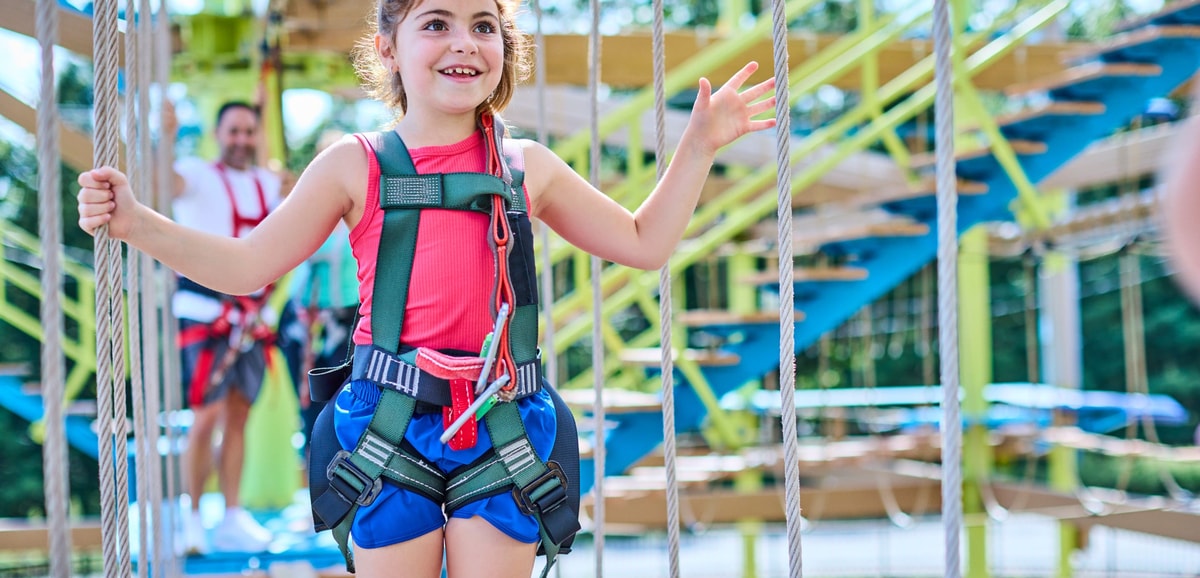Smiling girl in harness on a rope bridge