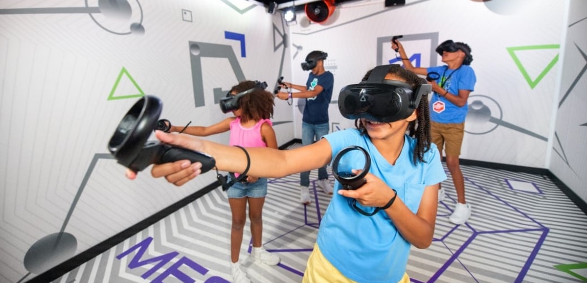 Kids wearing VR headsets play with controllers indoors