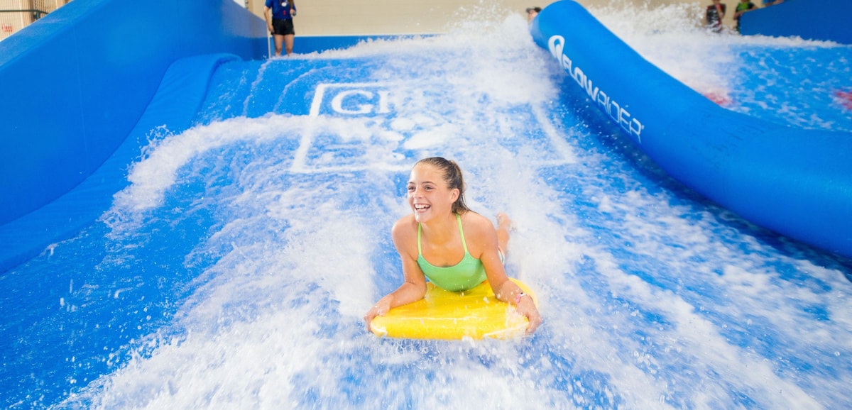 A child rides on a yellow boogie board in the water attraction 