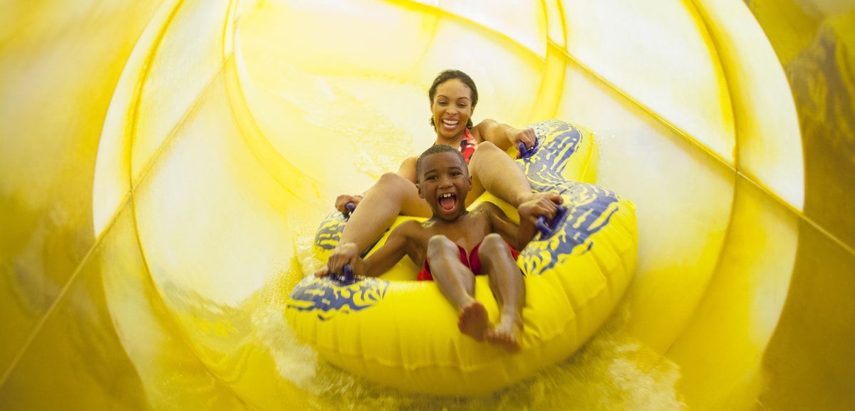 Mother and son in a tube racing down a yellow waterslide 