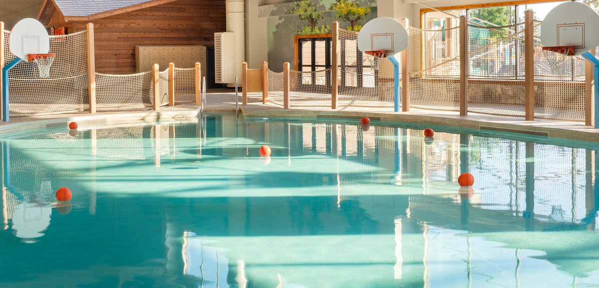 family playing basketball in indoor pool 