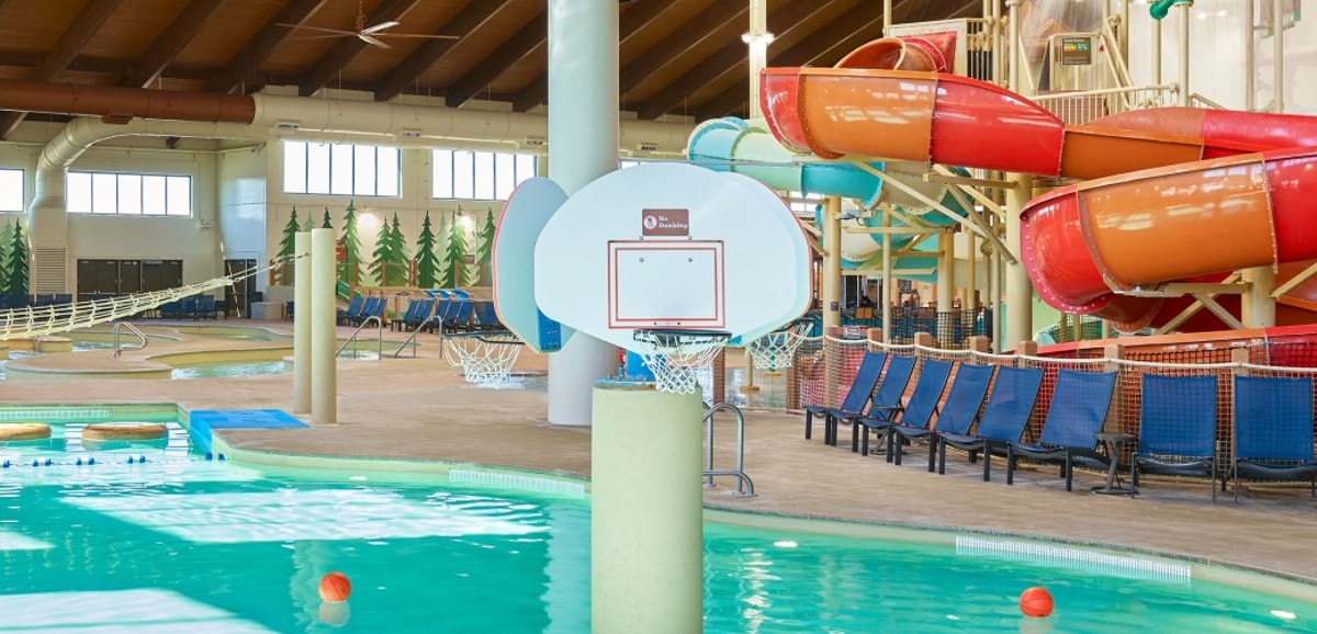 family playing basketball in indoor pool 