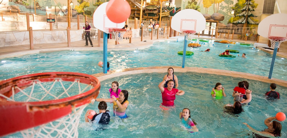 family playing basketball in indoor pool 
