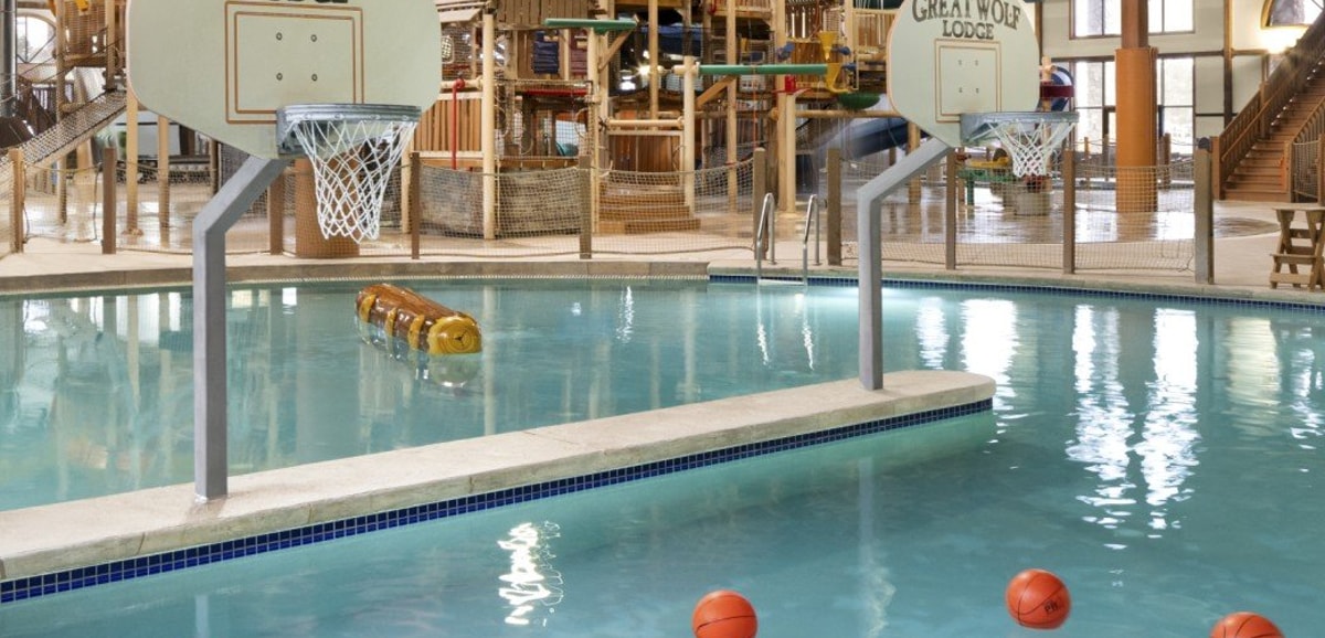 A large indoor water park featuring multiple slides and a basketball hoop for recreational activities.