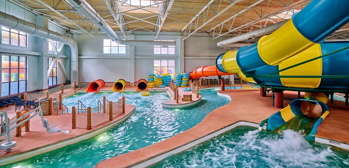 A father and son going down the Coyote Cannon water slide together on a yellow raft.