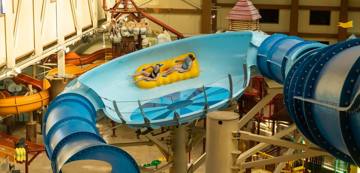 Two teenagers riding a yellow raft in an indoor water park