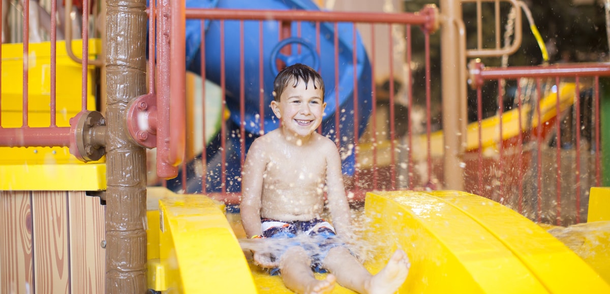 little boy about to go down a yellow kiddie slide