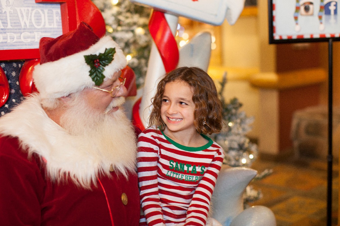 Little girl in holiday pajamas smiling at Santa