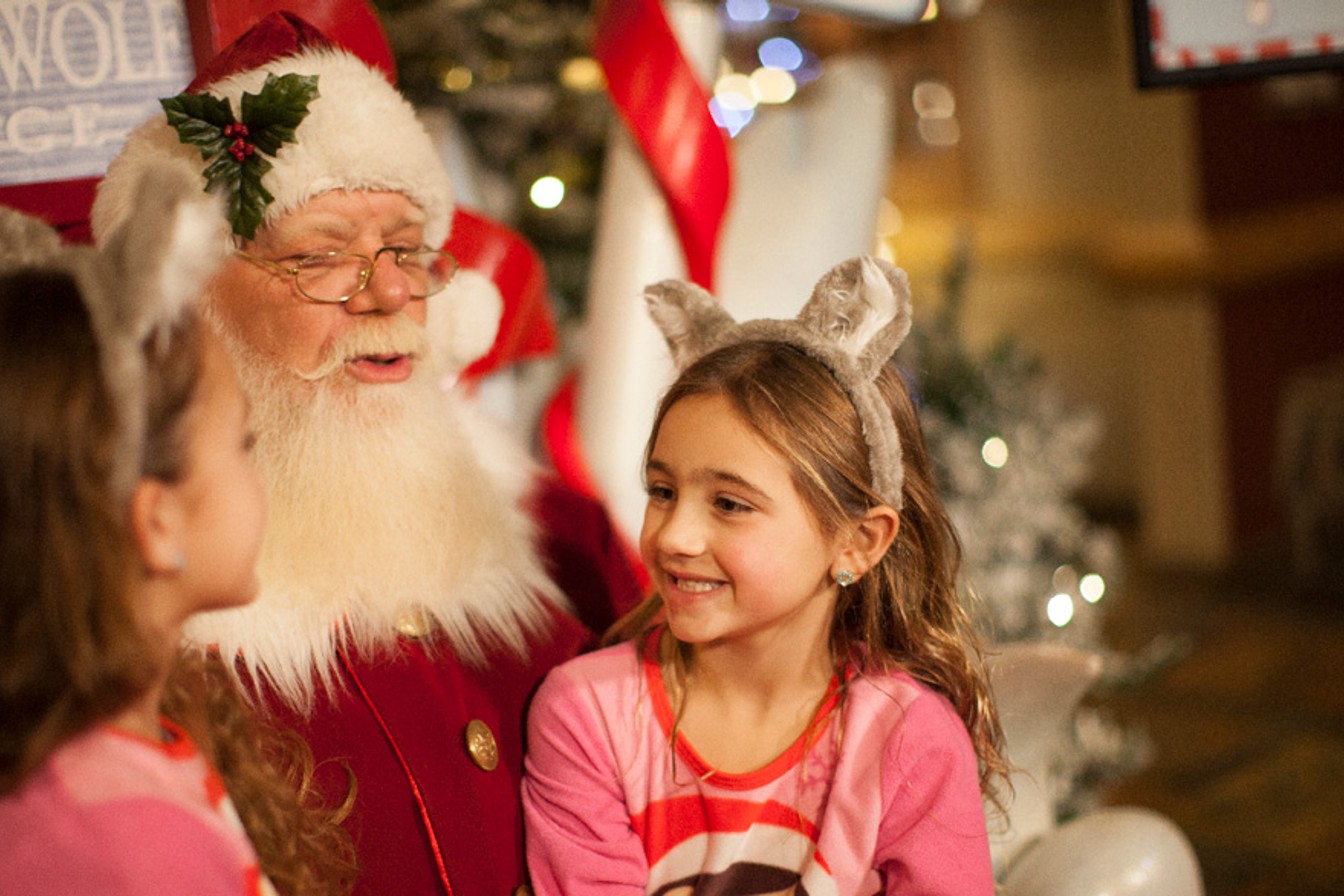 two kids smiling and sitting on Santa's laps