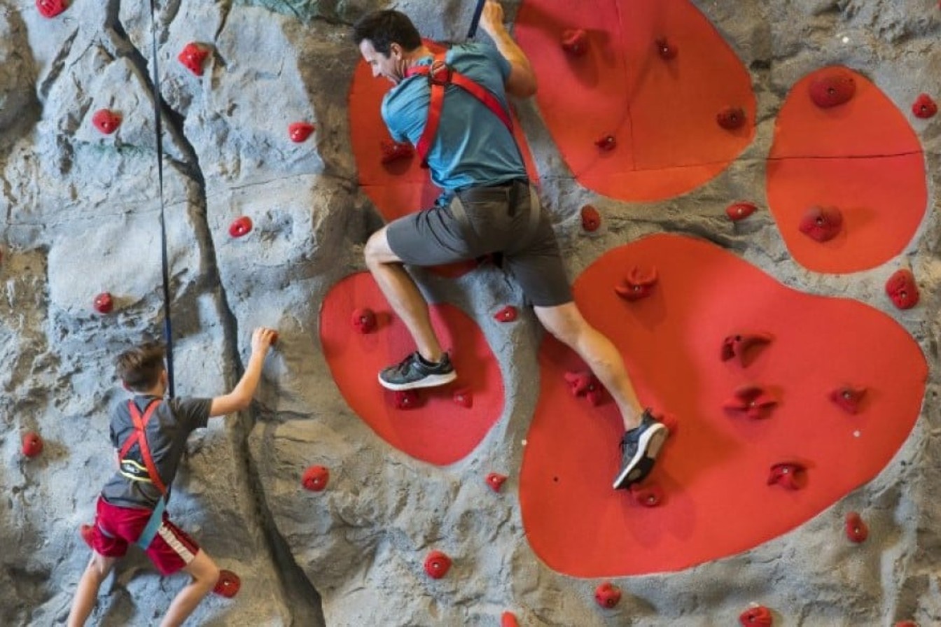 father and son climbing an indoor wall